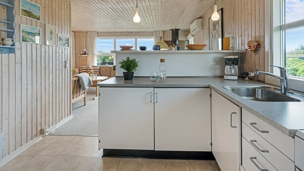 Una cocina moderna con paneles de madera, una isla central y vistas al exterior.
