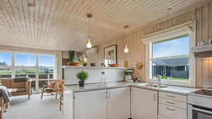 Una cocina moderna con armarios blancos, un ventanal y vistas al exterior.