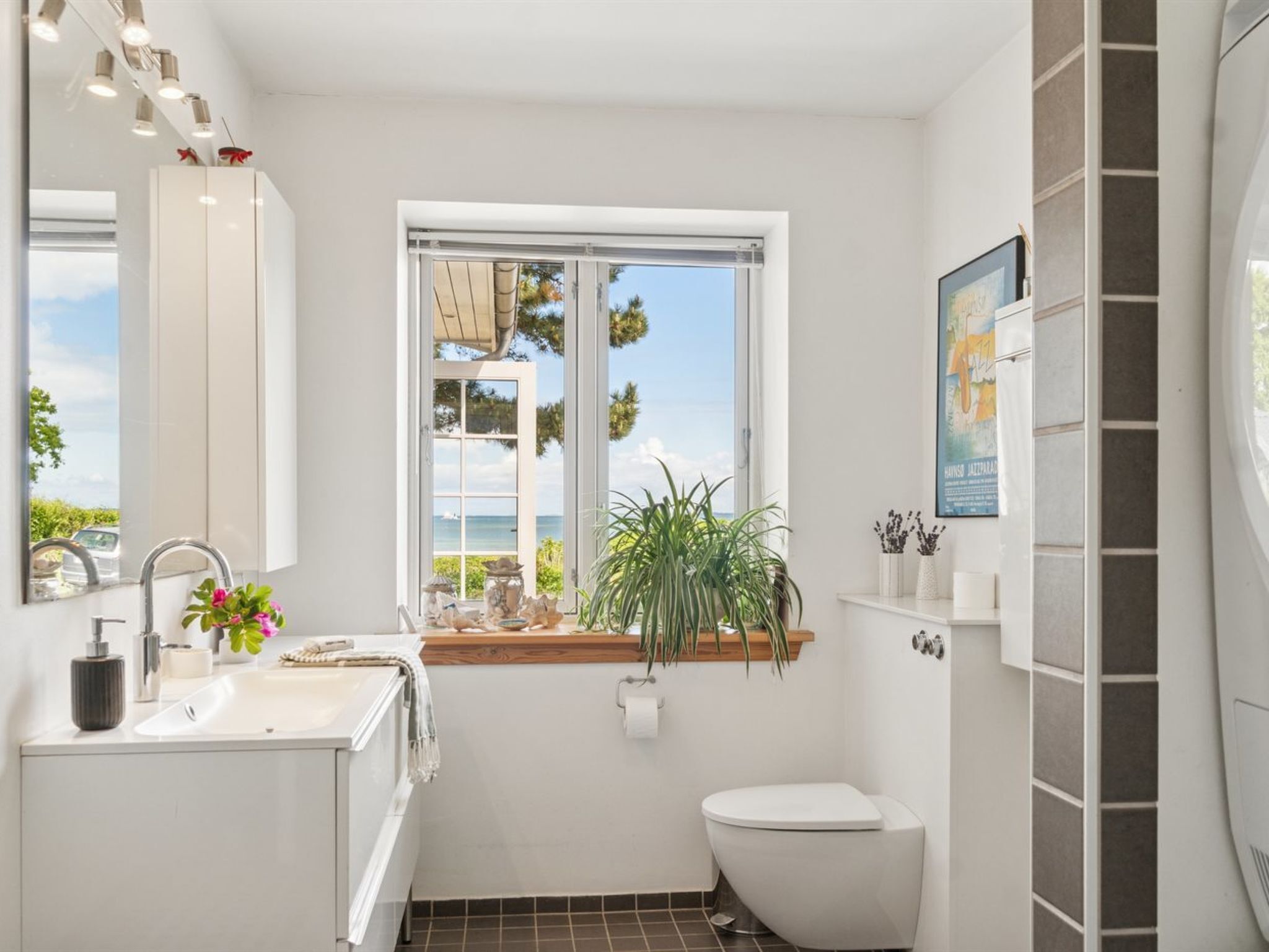 Une salle de bain moderne avec une grande fenêtre, un lavabo, des toilettes et un miroir.