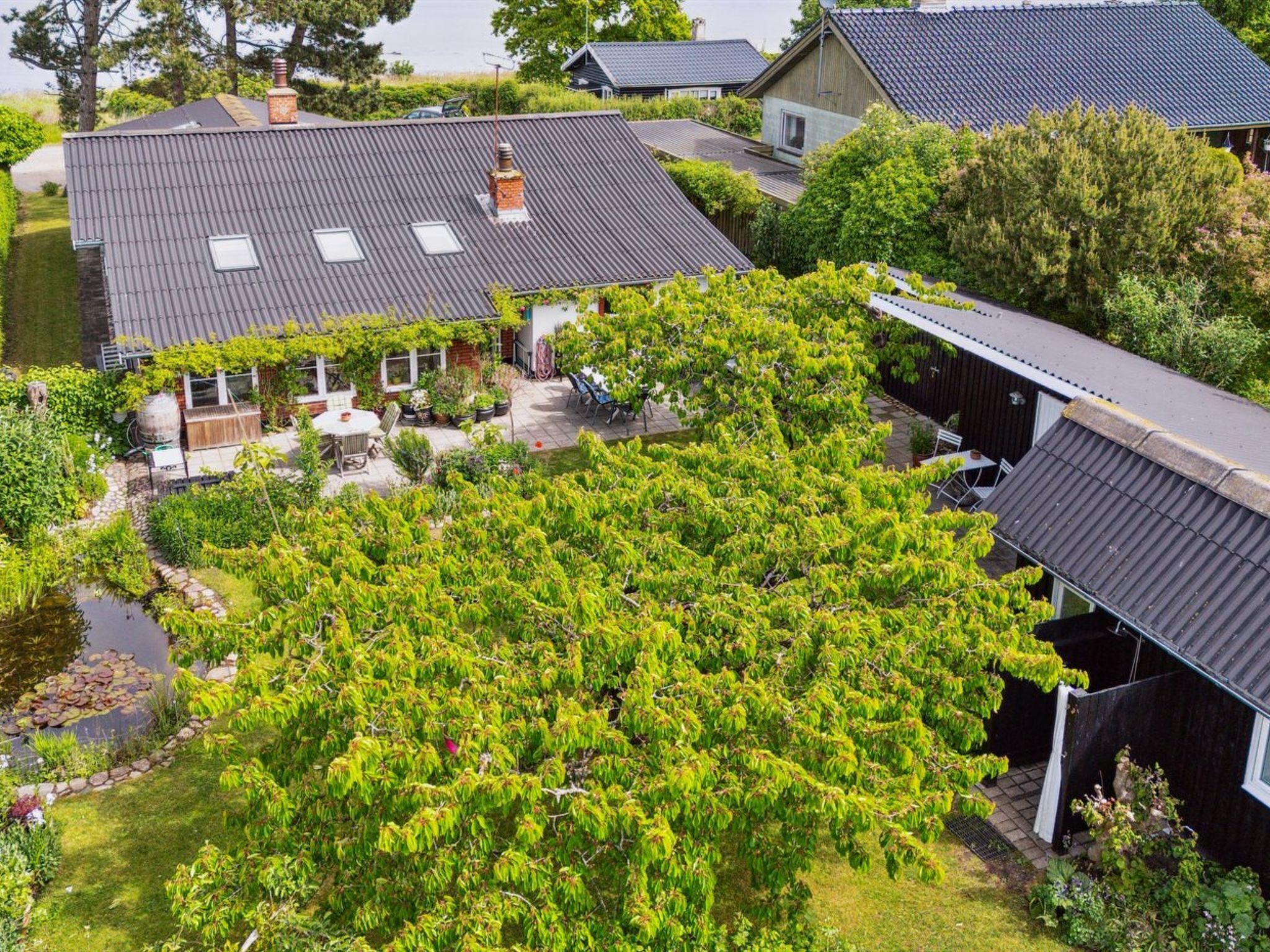 A residential area with multiple houses, a garden with a pond, and a patio area with outdoor furniture.