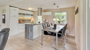 Eine moderne Küche mit Holzausstattung, einer zentralen Kochinsel und einem Essbereich mit Tisch und Stühlen.