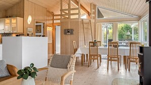 Ein gemütliches Blockhaus-Interieur mit Essbereich, Küche und einem großen Fenster mit Blick ins Freie.