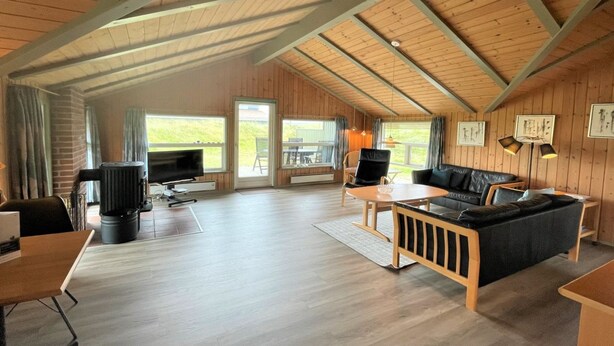 A spacious living area with a high ceiling, wooden walls, a sofa, a TV, and a dining table. - "Juha" -  from the sea by Interhome (Hvide Sande)