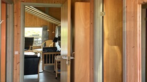 A wooden interior with a doorway leading to a room with a bed, chairs, and a table. - "Juha" -  from the sea by Interhome (Hvide Sande)