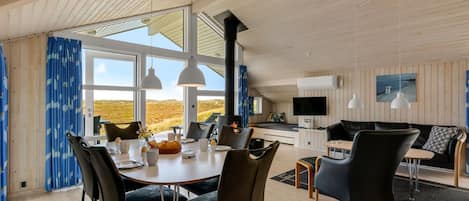 A spacious living area with a dining table, chairs, a sofa, and a television.