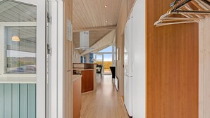 A corridor with wooden walls, a kitchen area, and a view of the outdoors.