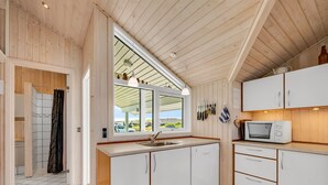 A modern kitchen with white cabinets, a sink, and a microwave.