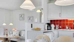 A modern kitchen with white cabinetry, a red backsplash, and pendant lighting.