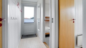 A narrow hallway with a door leading to a room with a bunk bed.