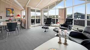 Un espace de vie moderne, à aire ouverte, doté d’une grande fenêtre, d’une table à manger et de sièges confortables.