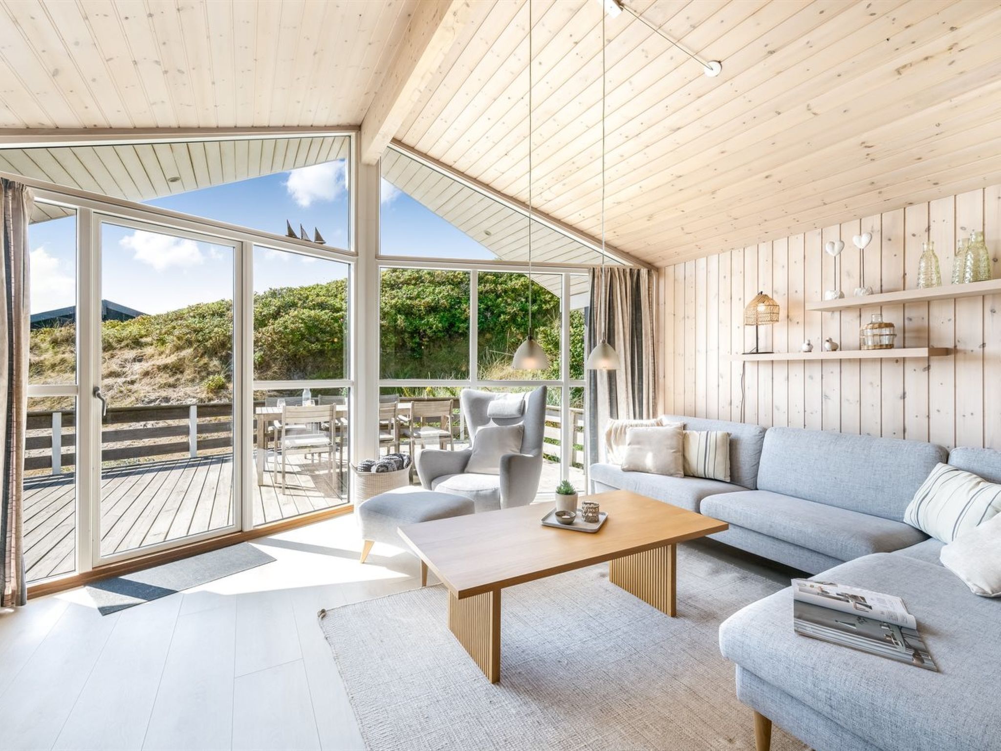 A spacious living area with a large window, a wooden ceiling, and a view of the outdoors.