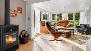 Un salon moderne doté d’une cheminée, de sièges confortables et de grandes fenêtres offrant une vue sur l’extérieur.