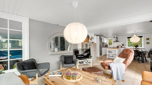 Un salon moderne avec une table basse en bois, des canapés gris et un fauteuil en cuir.