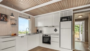 Una cocina moderna con armarios blancos, horno empotrado y microondas.