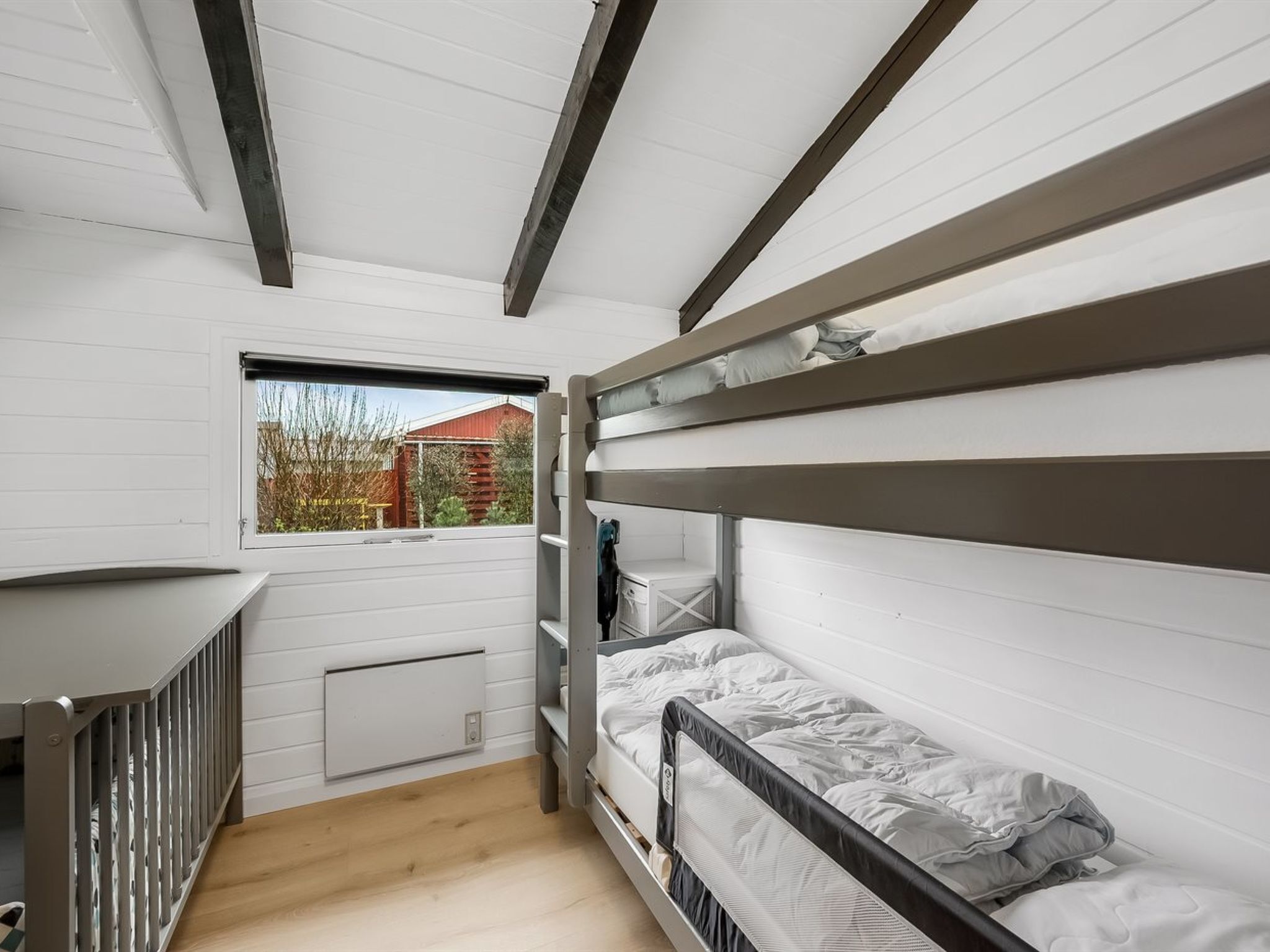 Habitación pequeña con literas, una ventana y un radiador.
