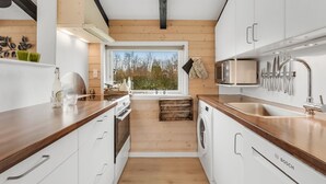 Una cocina moderna con armarios de madera, una lavadora Bosch y un amplio ventanal con vistas al exterior.