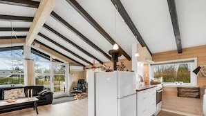 Una cocina moderna con una isla grande, vigas de madera y vistas al exterior.