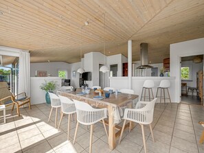 Un comedor amplio con una mesa de madera, sillas blancas y luces colgantes.