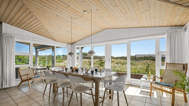 Une salle à manger spacieuse avec un plafond en bois, de grandes fenêtres et une vue sur le paysage.