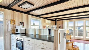 A modern kitchen with wooden paneling, a built-in oven, and a large window.