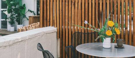 A round table with chairs and a potted plant on a wooden deck.