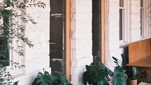 A building with a stone facade, a wooden door with a sign, and potted plants outside. - guesthouse by good neighbor (Baltimore)