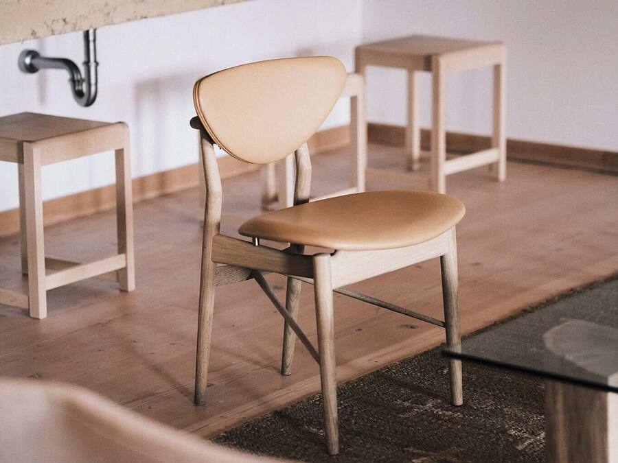 A modern bathroom with a wooden vanity, a chair, and a small stool.