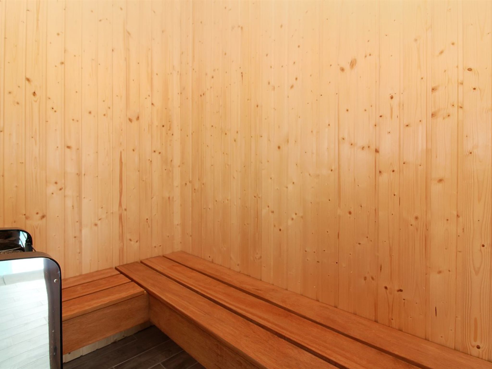 Un sauna avec des murs et des bancs en bois.