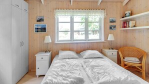 A bedroom with two beds, wooden walls, a window with a view, and a bookshelf. - "Nela" - 300m from the sea by Interhome (Grenaa)