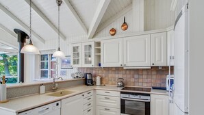 A kitchen with white cabinets, a Bosch dishwasher, a stove, and a coffee maker. - "Nela" - 300m from the sea by Interhome (Grenaa)