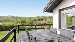 Ein Balkon mit Tisch und Stühlen, mit Blick auf eine üppige grüne Landschaft und einen Hügel in der Ferne.