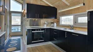 A modern kitchen with dark cabinets, a stainless steel range, and a large window. - "Styrbiorn" - 100m from the sea by Interhome (Løkken)