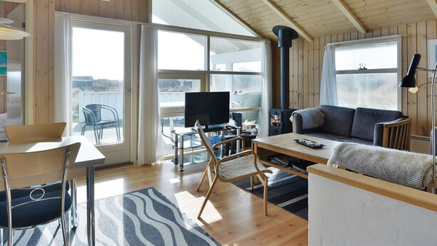 A cozy cabin interior with a wooden ceiling, a fireplace, a television, and a dining area. - "Styrbiorn" - 100m from the sea by Interhome (Løkken)