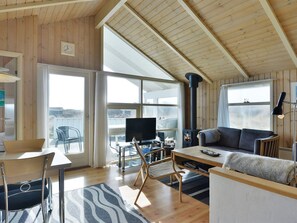 A cozy cabin interior with a wooden ceiling, a fireplace, a television, and a dining area. - "Styrbiorn" - 100m from the sea by Interhome (Løkken)