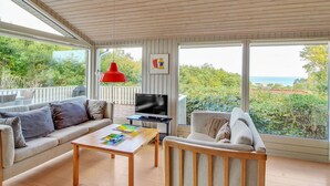 A spacious living room with a wooden ceiling, a sofa, a coffee table, a TV, and large windows offering a view of the outdoors. - "Ludewiga" - 350m from the sea by Interhome (Glesborg)