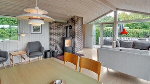 A modern interior with a wooden ceiling, a brick fireplace, a dining table with chairs, and a sofa with cushions. - "Ludewiga" - 350m from the sea by Interhome (Glesborg)