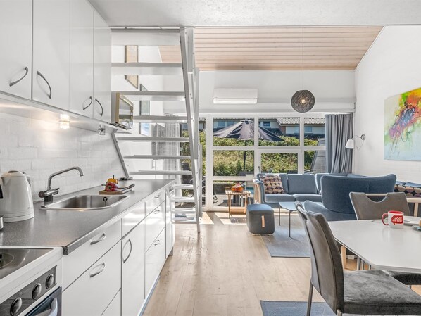 A modern kitchen with a dining area, large windows, and a view of the outdoors.