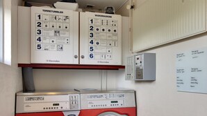 A laundry room with two Electrolux washing machines, a control panel, and instructional posters. - "Soufiane" - 100m from the sea by Interhome (Vejers Strand)