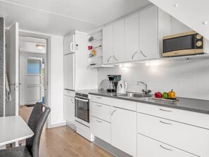 A modern kitchen with white cabinetry, a built-in microwave, a coffee maker, and a sink.