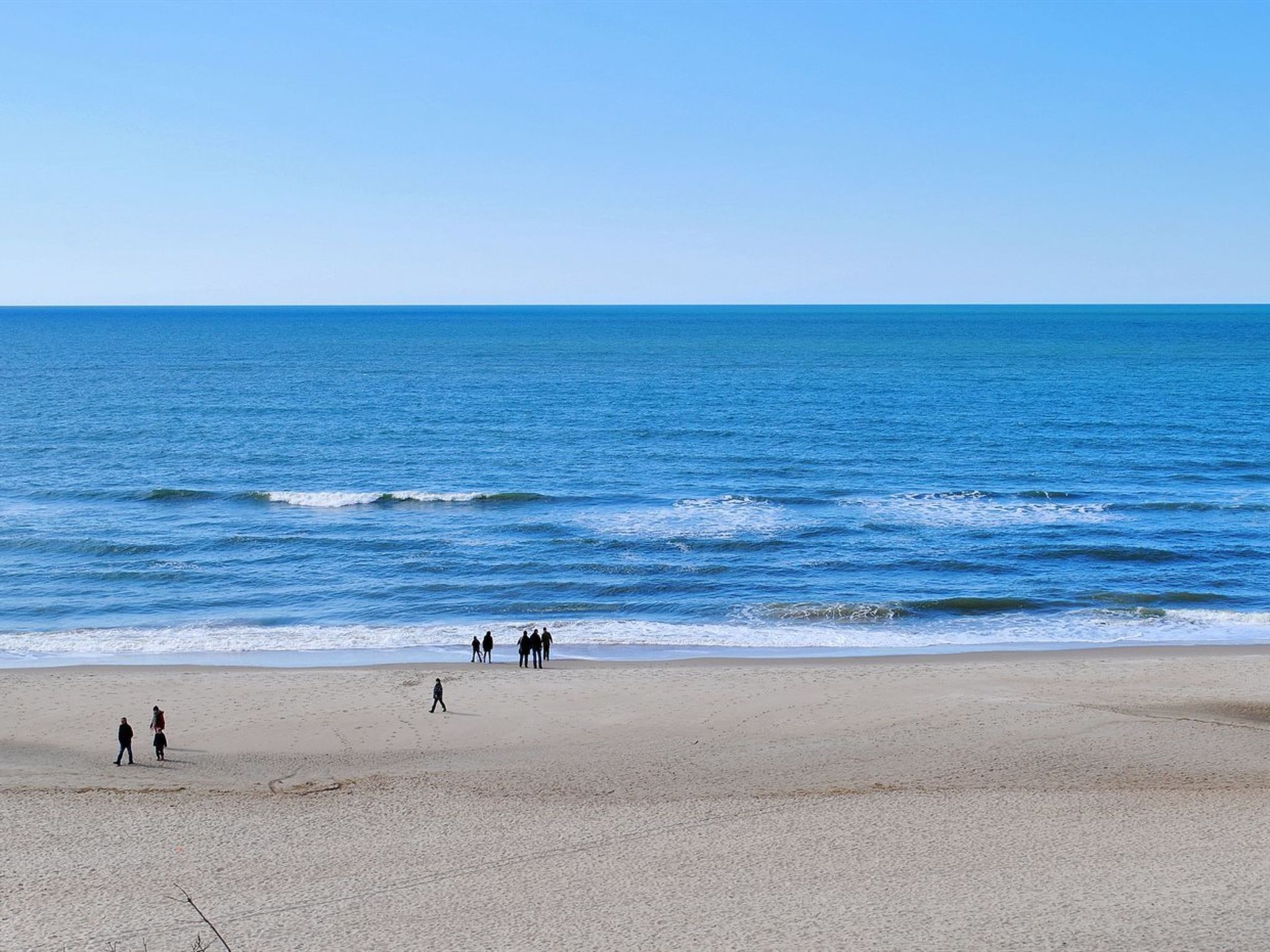 Une plage où des gens se promènent le long du rivage.
