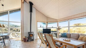 A spacious room with a fireplace, a dining area, and a sofa with a view of the outdoors.