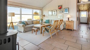 A spacious living area with a large window, a fireplace, a dining table with chairs, and a sofa.