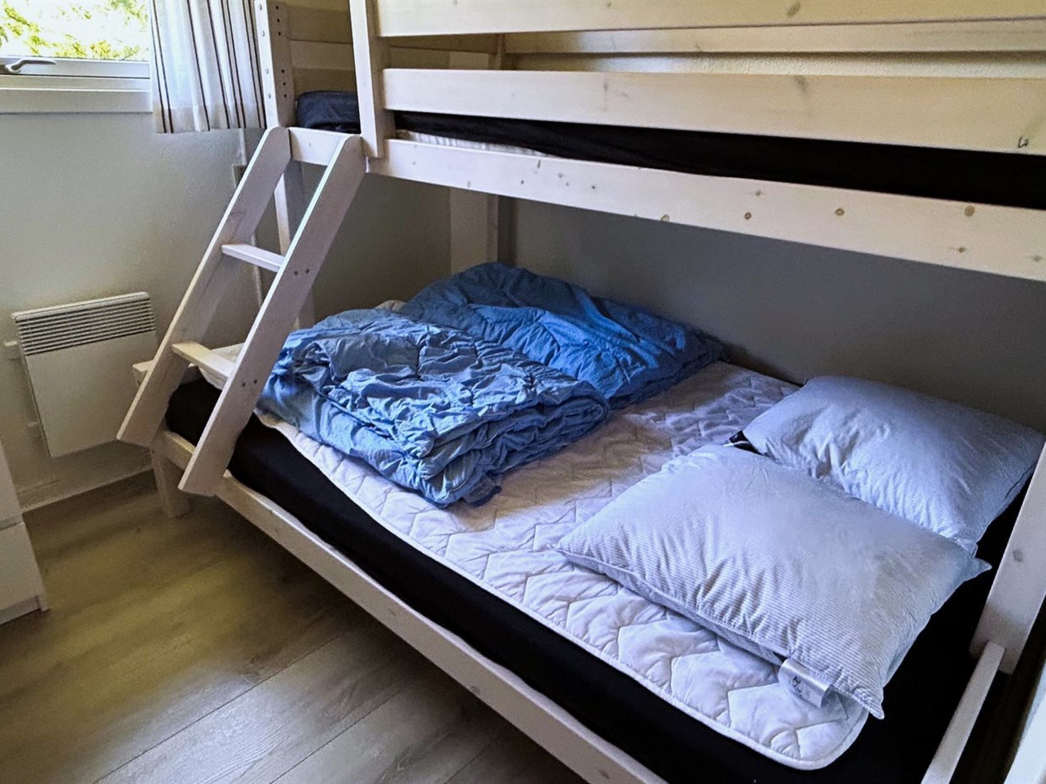 A bunk bed with a ladder, a blue blanket, and a pillow.