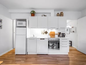 Une cuisine moderne avec des meubles blancs, un four encastré et un micro-ondes.