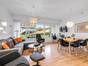 Un espace de vie moderne comprenant un canapé, une table à manger, des chaises et un téléviseur.