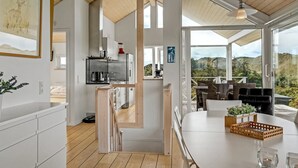 Eine moderne Küche mit Holzbalkendecke, eine Essecke mit Aussicht und eine Treppe, die zu einer anderen Ebene führt.
