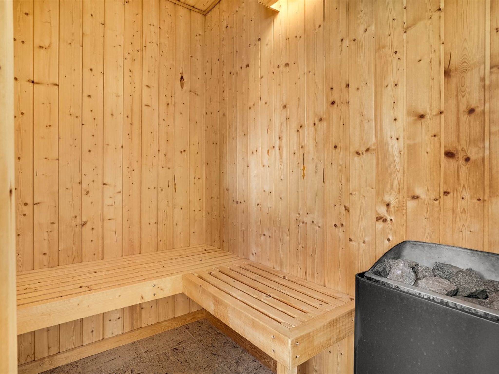 Een houten sauna met een bank en een stenen heater.