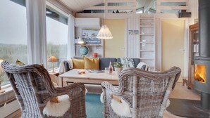 Un salon chaleureux avec des meubles en osier, une table centrale et une cheminée.