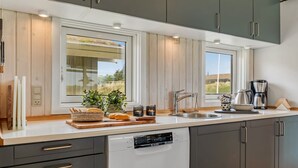 A modern kitchen with grey cabinets, a dishwasher, a sink, and a coffee maker.