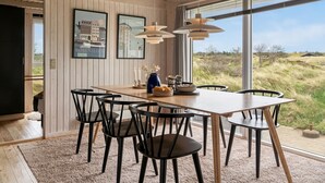 A dining area with a wooden table, black chairs, and pendant lights.